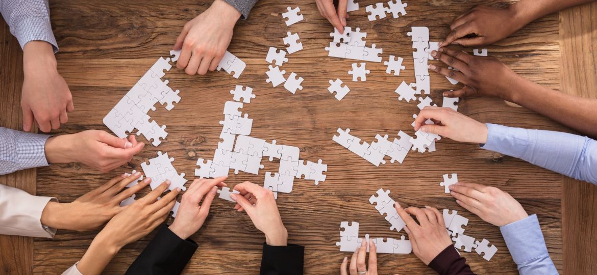 High,Angle,View,Of,Businesspeople,Hand,Solving,Jigsaw,Puzzle,On